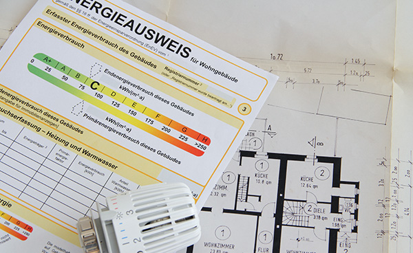 Energieausweis, ein Energieausweis liegt über einem Architektenplan auf dem Tisch